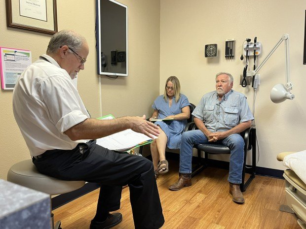 Kırsal hastanelerin kanser önleme programlarını azaltmasıyla küçük kasabalardaki hastalar büyük engellerle karşı karşıya kalıyor 4 Fred Hardwicke, an oncologist, reviews medical notes with Dennis and Mary Ellen Woodward. Dennis has a type of non-Hodgkin lymphoma. (Charlotte Huff/KFF Health News/TNS)