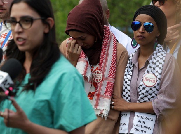 Taahhüt vermeyen delegeler ve 'Takım' üyeleri, Filistinli bir Amerikalının konuşma hakkı almasını talep etmek için DNC'de oturma eylemi yaptı 2 U.S. Rep. Ilhan Omar, right, comforts Asma Nizami, an uncommitted delegate from Minnesota, as they listen to Dr. Tammy Abughnaim speak about the atrocities she's witnessed while working in Gaza, at Park 578 on Aug. 21. 2024, in Chicago. Dr. Abughnaim and others gathered to ask Democratic leaders to stop supplying weapons to Israel. (Stacey Wescott/Chicago Tribune)
